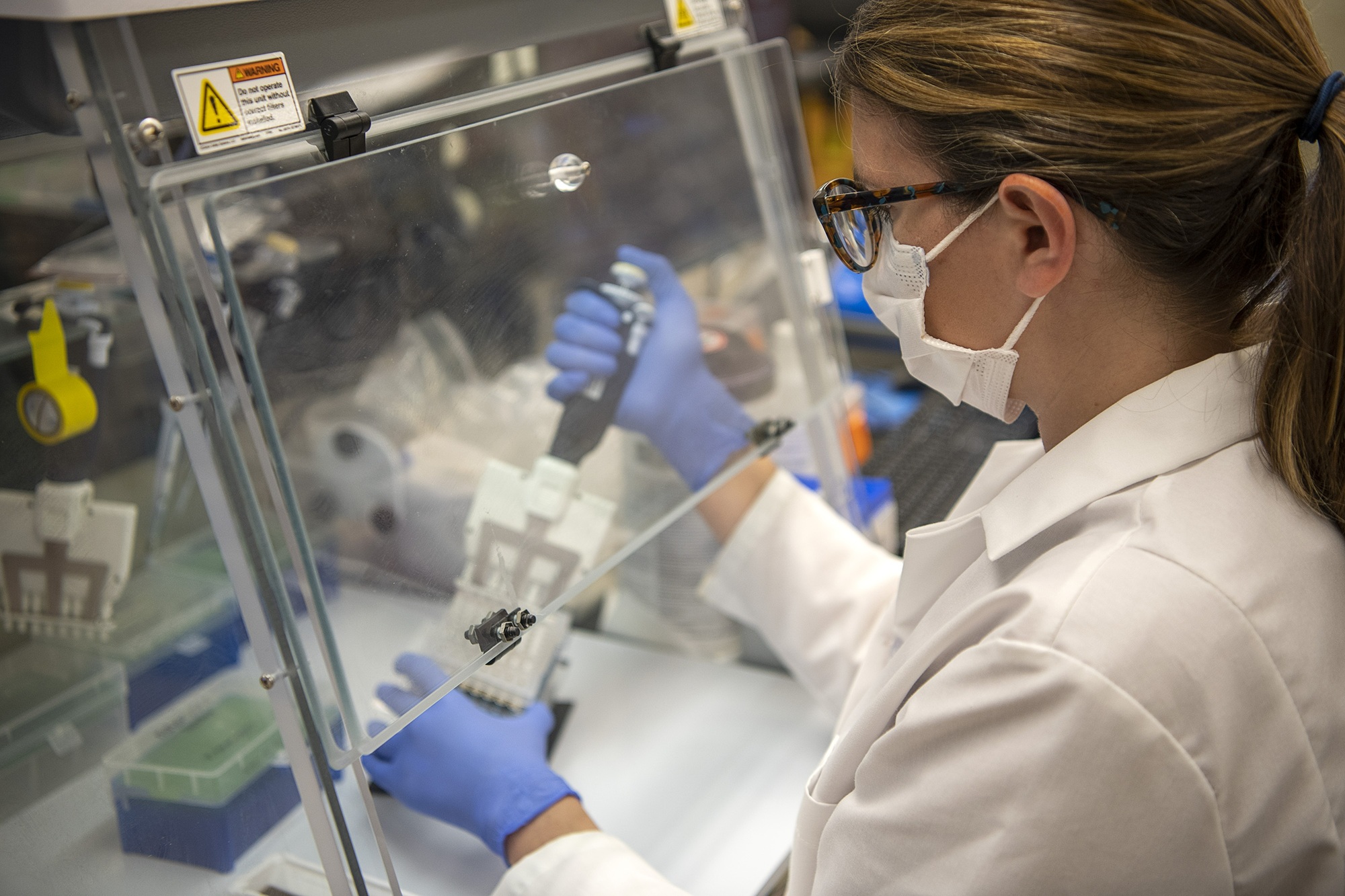 Researcher pipeting in a containment hood